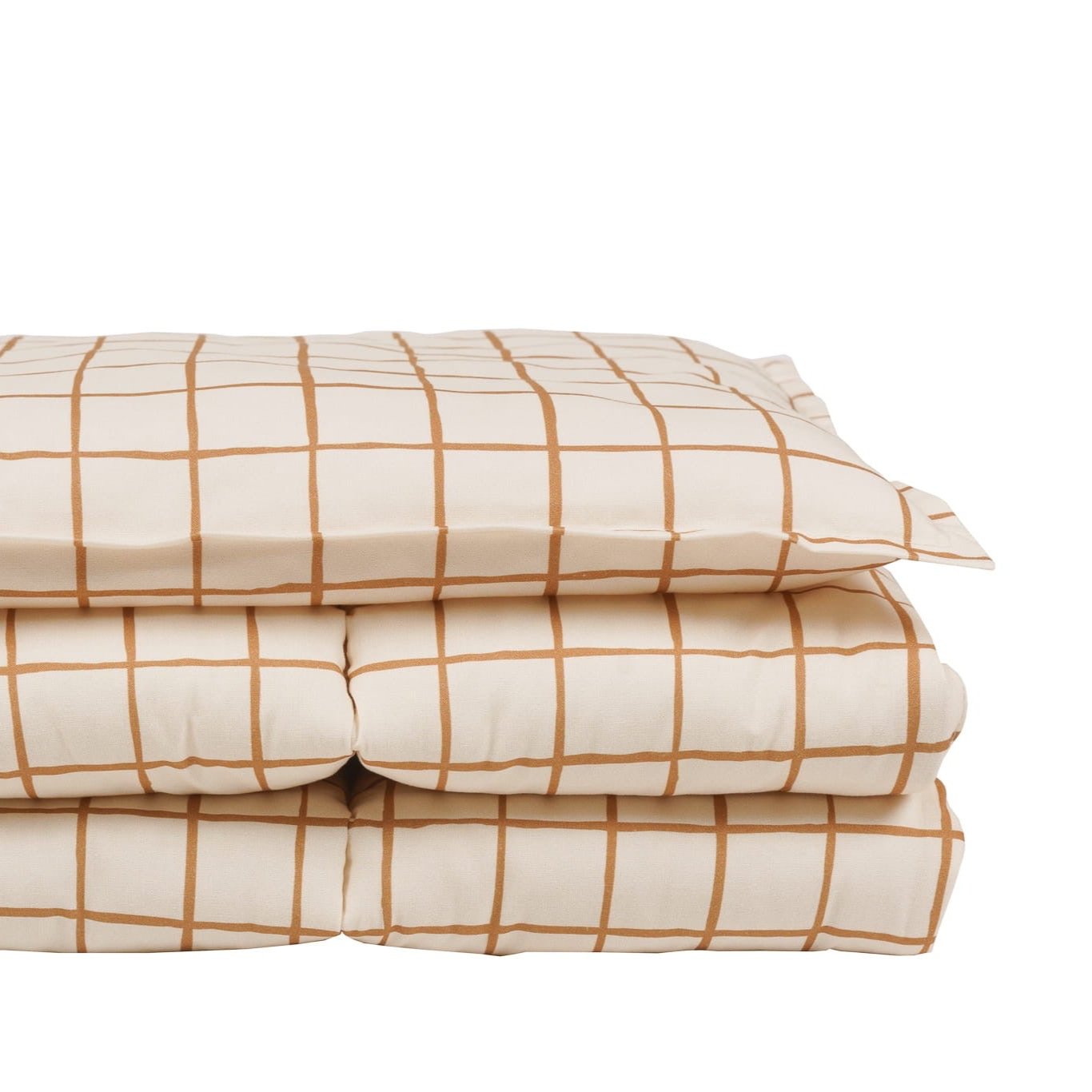 Side view of the camel check bedding set, showcasing the plush pillow and quilt folded together.