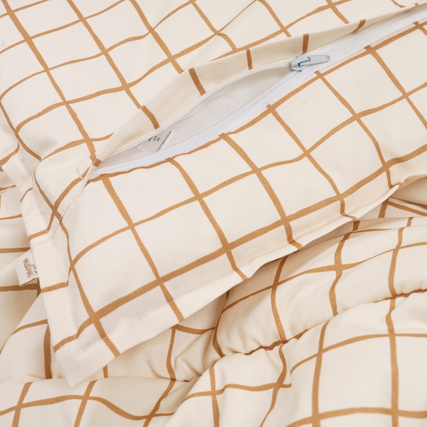 Close-up of a camel check bedding pillowcase with a visible zipper detail on soft cotton fabric.